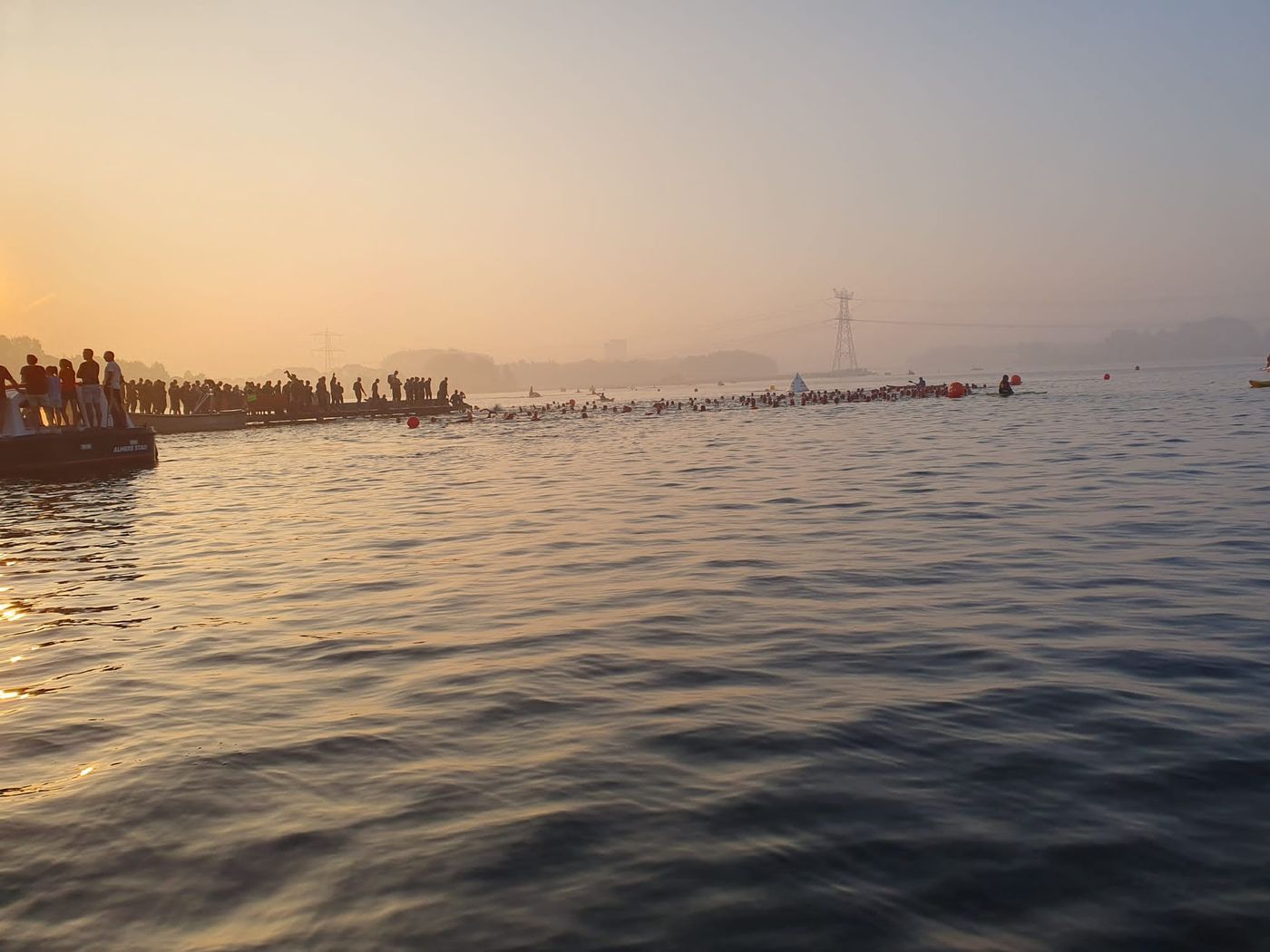 Zwemstart van een triathlon in open water bij zonsopkomst